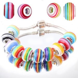 May include: A silver charm bracelet with colorful striped beads. The beads are arranged in a rainbow pattern and have a silver charm in the center.