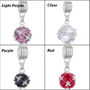 May include: Four silver charm beads with a dangling crystal ball. The crystal balls are in the colours light purple, clear, black, and red.