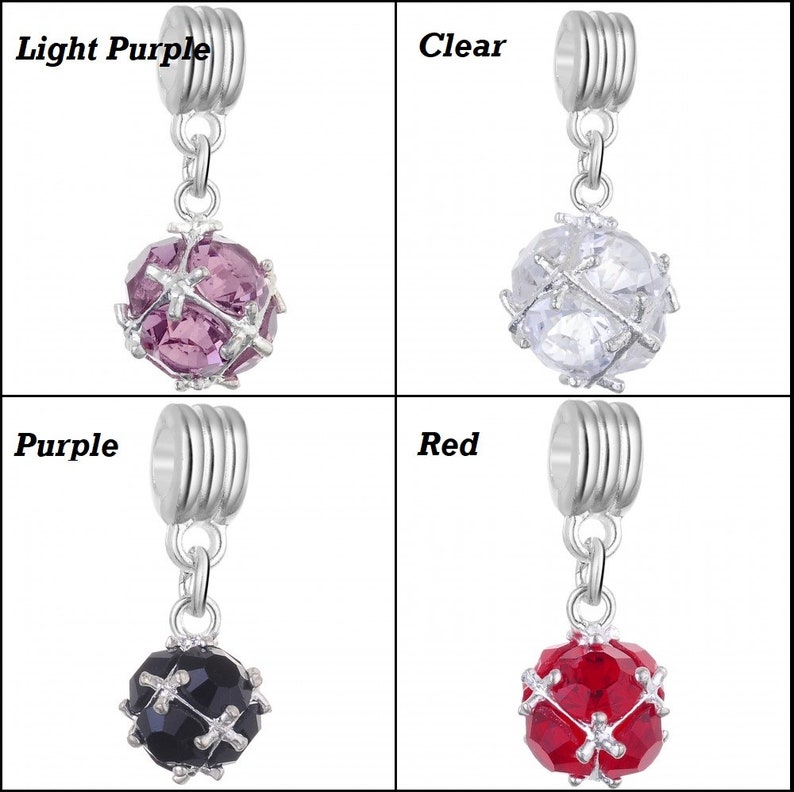 May include: Four silver charm beads with a dangling crystal ball. The crystal balls are in the colours light purple, clear, black, and red.
