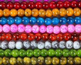 May include: A close-up view of multiple strands of colorful, round beads. The beads are arranged in rows, showcasing a variety of colors including purple, red, yellow, blue, pink, orange, white, green, and black. Each bead has a unique marbled pattern.
