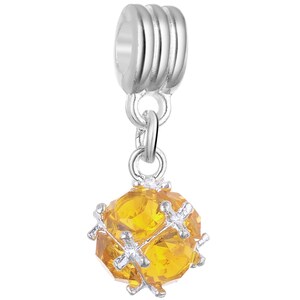 May include: A silver charm featuring a clear yellow crystal ball surrounded by silver accents. The charm has a silver loop at the top for attaching to a bracelet or necklace.