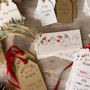 May include: A collection of brown and white Christmas gift tags with festive designs. Some tags feature a North Pole theme with the text "Special Delivery" and a checklist for naughty or nice. Other tags have a Christmas tree design, a gnome design, and the text "Merry Christmas".