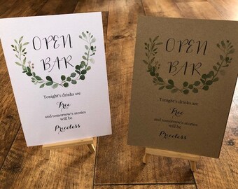 May include: Two signs with a green leafy wreath design and the text "OPEN BAR" on a white and brown background. The text below the wreath reads "Tonight's drinks are Free and tomorrow's stories will be Priceless."
