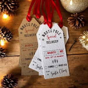 May include: Four white and brown gift tags with red ribbon. The tags are shaped like a house and have the text "North Pole Special Delivery" printed on them. The tags have checkboxes for "Naughty" or "Nice", "Chimney" or "Magic Key", and a space for the date and from.