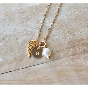 以下が含まれることがあります： 小さな真珠のチャーム、金の天使の羽根のチャーム、そして「H」の文字が刻まれた金の円盤のチャームが付いた金のネックレスです。