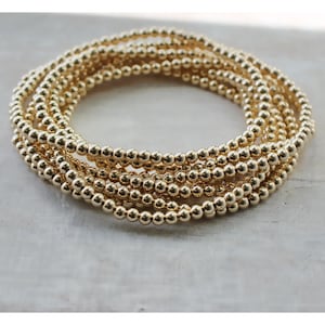 May include: A gold-toned bracelet made of multiple strands of small, round beads.