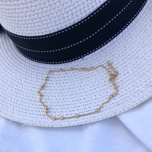Gold Filled chain with beads anklet laid on a white hat on the beach.