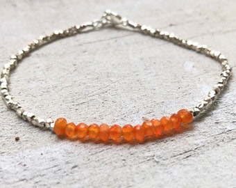 May include: A silver chain bracelet with a row of orange carnelian beads.