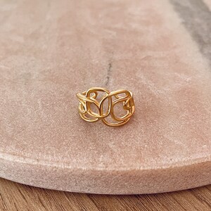 Peut inclure: Une bague en or avec un design délicat et complexe. La bague est faite d'une seule pièce de métal qui est torsadée et bouclée pour créer un look unique et élégant.