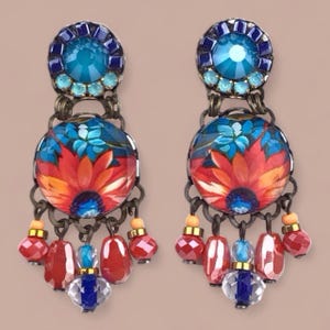 Puede incluir: Un par de pendientes colgantes con un diseño floral. Cada pendiente tiene una gema azul en la parte superior, un colgante redondo con un patrón floral rojo y azul, y cuentas rojas y azules colgantes. Los pendientes tienen un metal color bronce.