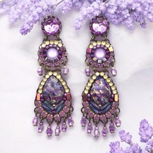 May include: Purple and gold dangle earrings with iridescent teardrop-shaped stones and multiple layers of beads.