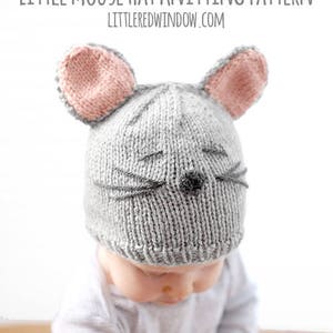 May include: A gray knitted hat with pink ears and a mouse face. The hat is being worn by a baby.