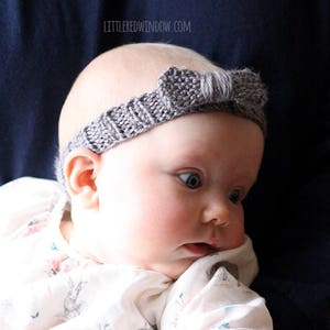 chubby baby with wide blue eyes wearing a medium dusty purple ribbed knit headhand with a purple knit bow on the front and being held in front of a dark navy blue background and looking off to the right