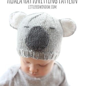 Chubby baby in a gray shirt wearing a gray knit hat that looks like a koala looking down at her lap