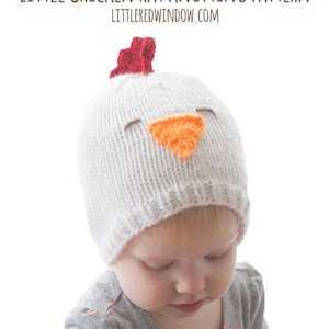 Puede incluir: Un gorro de bebé blanco tejido con un diseño de cara de pollo. El gorro presenta un pico naranja, ojos marrones y una cresta roja. El texto "LITTLE CHICKEN HAT KNITTING PATTERN" y "LITTEREDWINDOW.COM" son visibles.