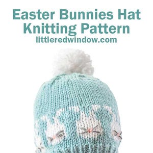 May include: A light blue knitted hat with a white pom pom on top. The hat features a pattern of white bunny faces on the front. The hat is being worn by a child.
