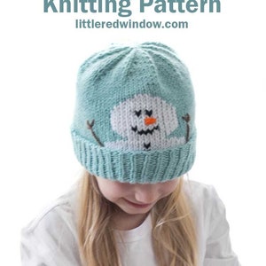 May include: A child wearing a teal blue knitted hat with a white snowman face and orange carrot nose. The hat has black eyes, a black mouth, and two black sticks for arms. The text "Silly Snowman Hat Knitting Pattern" and "littleredwindow.com" is above the hat.