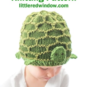Puede incluir: Un niño lleva una gorra de punto verde en forma de tortuga con nariz y ojos marrones. La gorra tiene un patrón de caparazón texturizado. El texto "Turtle Hat Knitting Pattern littleredwindow.com" está por encima de la cabeza del niño.