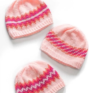 May include: Three pink knitted hats with colorful stripes. The hats have a gradient of pink, orange, and red. The hats are on a white background. Fiery Fades Hats Knitting Pattern littleredwindow.com