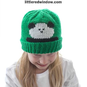 May include: A green knitted hat with a white panda face on the front. The hat is being worn by a child with long blonde hair. The text "Peekaboo Panda Hat Knitting Pattern" is at the top of the image.