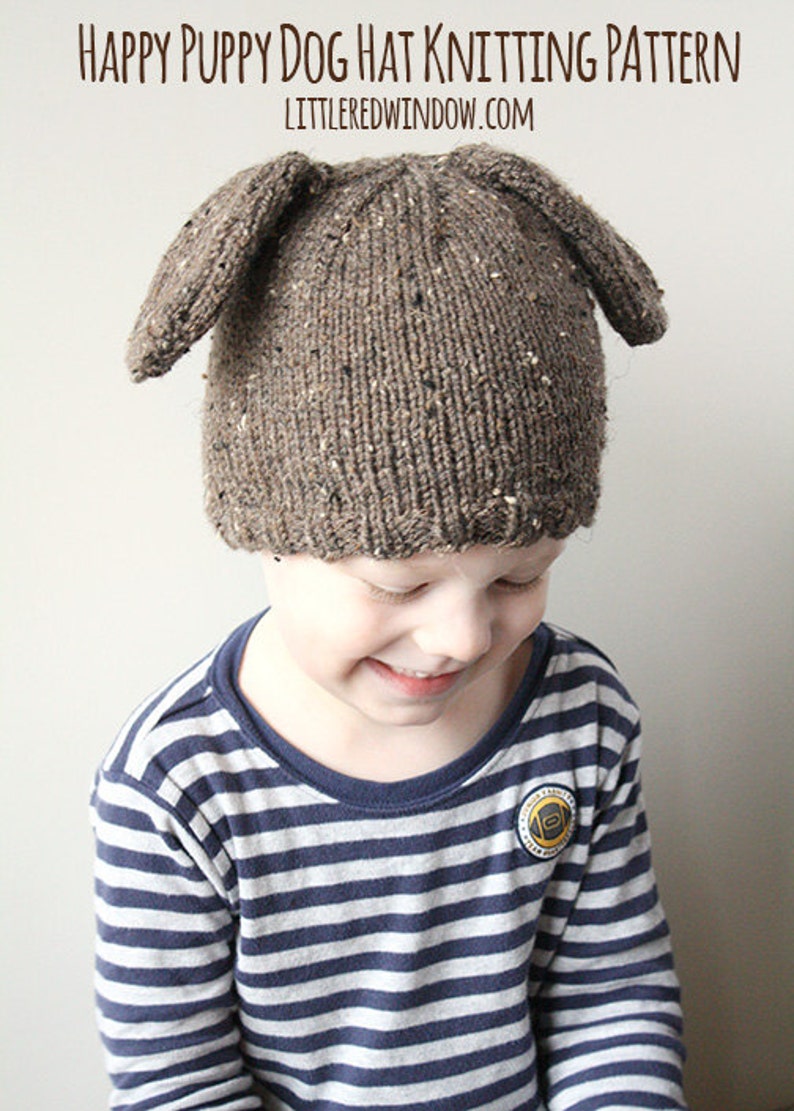 Puede incluir: Un ni&ntilde;o lleva un gorro de punto marr&oacute;n con orejas ca&iacute;das en forma de cachorro. El gorro tiene un patr&oacute;n moteado. El ni&ntilde;o lleva una camisa a rayas azul y blanca.