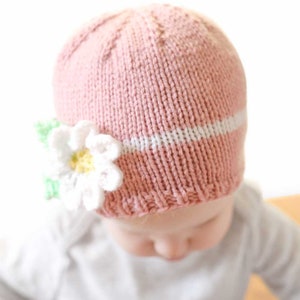 closeup of light pink knit spring daisy flower hat knitting pattern on a baby