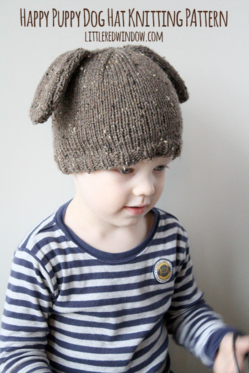 Puede incluir: Un ni&ntilde;o lleva un gorro de punto marr&oacute;n con orejas ca&iacute;das con forma de cachorro. El gorro tiene una textura moteada. El ni&ntilde;o lleva una camisa a rayas azules y blancas.