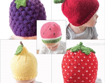 May include: Four knitted baby hats shaped like different fruits: a purple grape, a red apple, a pink watermelon, and a red strawberry. Each hat has a green knitted leaf on top.