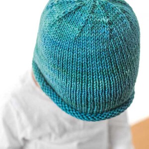 view from above of teal hand dyed yar knit rolled brim hat pattern to show the decreases