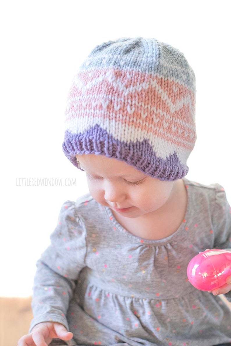 baby wearing knit easter egg hat and holding one pink easter egg