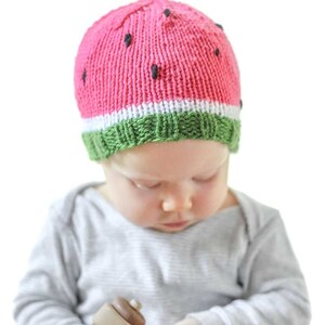 baby wearing a fun knit hat that looks like a watermelon slice complete with seeds looking down at their hands