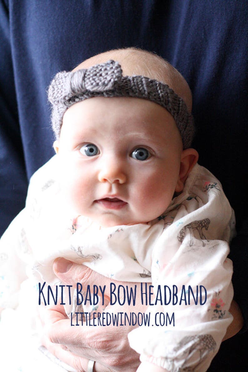 chubby baby with wide blue eyes wearing a medium dusty purple ribbed knit headhand with a purple knit bow on the front and being held in front of a dark navy blue background
