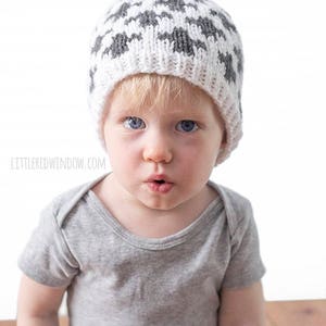 Puede incluir: Un ni&ntilde;o peque&ntilde;o con un gorro de punto gris y blanco con un pomp&oacute;n en la parte superior. El gorro tiene un patr&oacute;n geom&eacute;trico.