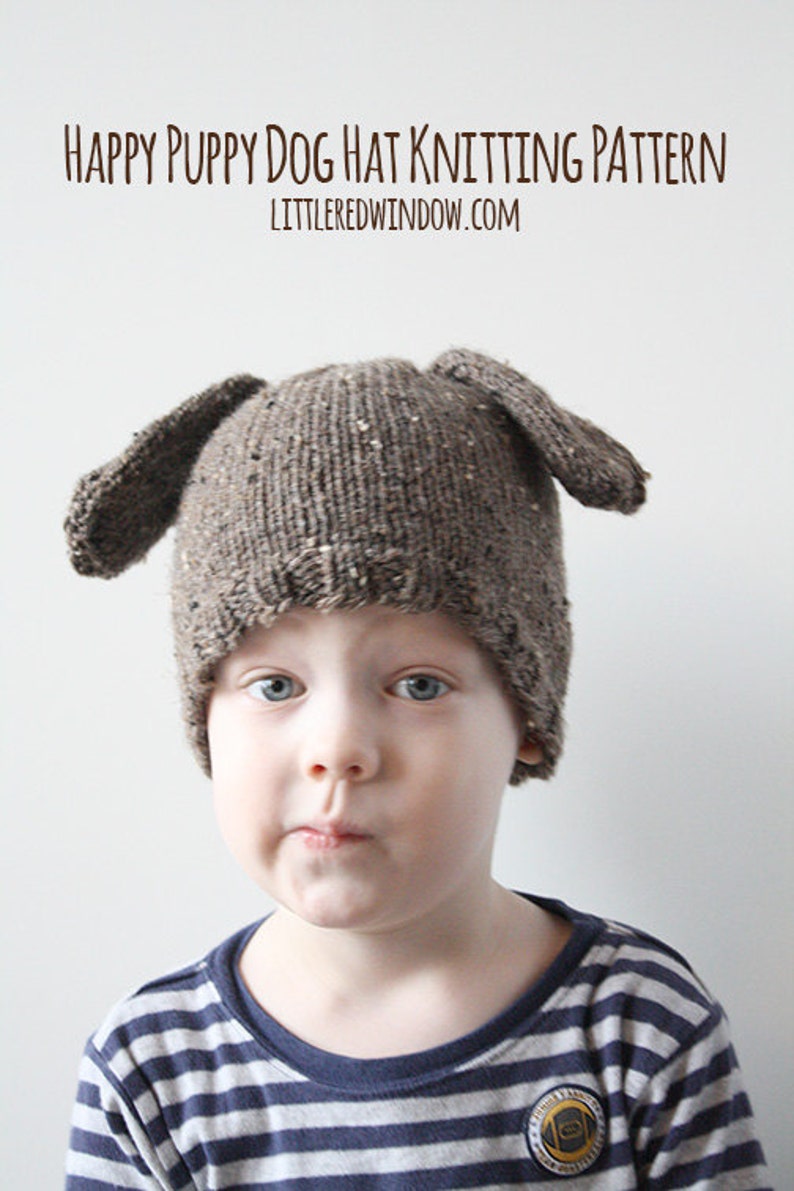 Puede incluir: Un ni&ntilde;o lleva un gorro de punto marr&oacute;n con orejas ca&iacute;das con forma de perro. El gorro tiene un patr&oacute;n moteado marr&oacute;n y blanco. El ni&ntilde;o lleva una camisa a rayas azul y blanca. El texto "HAPPY PUPPY DOG HAT KNITTING PATTERN LITTLE RED WINDOW.COM" est&aacute; en la parte superior de la imagen.