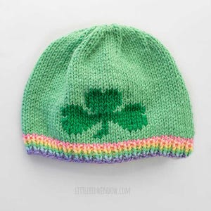 May include: Green knitted hat with a green shamrock design and a rainbow colored brim.