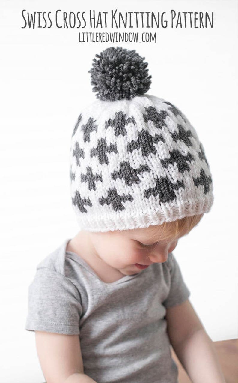 Puede incluir: Un gorro de punto blanco y gris con un patr&oacute;n de cruz suiza y un pomp&oacute;n gris en la parte superior. El gorro lo lleva puesto un ni&ntilde;o.