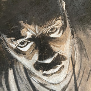 May include: A black and white charcoal drawing of a person's face. The person has a serious expression with furrowed brows and intense eyes. The drawing is done in a realistic style.
