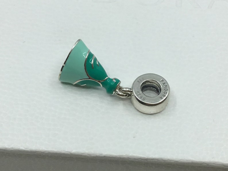 Puede incluir: Un charm de plata con un dise&ntilde;o de vestido en esmalte verde y azul. El charm tiene una cuenta redonda de plata con el texto "Pandora" y "ALE 925" en &eacute;l.