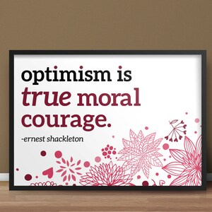 Op de afbeelding: Een zwart ingelijst print met een witte achtergrond en roze bloemenontwerp. De quote "optimisme is ware morele moed." is in zwarte tekst gedrukt met de toeschrijving "Ernest Shackleton" eronder.