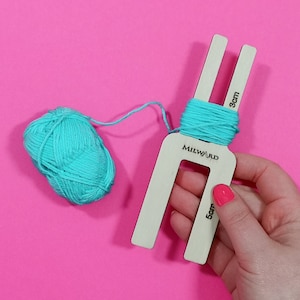 May include: A wooden pom-pom maker with a turquoise yarn ball and a label that reads "Milward" and includes measurements in centimetres.