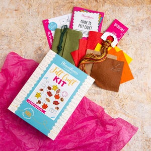 May include: A craft kit for making an autumn garland. The kit includes felt pieces in various fall colors, embroidery floss, needles, and a guide to felt craft. The box features a colorful illustration of the finished garland.