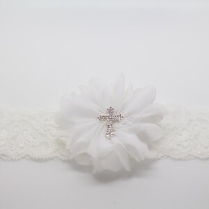 May include: Ivory lace garter with a white chiffon flower and a rhinestone cross. The garter is a delicate accessory, perfect for a wedding or special occasion. The lace band is approximately 1 inch wide.