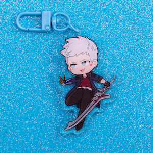 May include: A blue keychain clip and a chibi-style acrylic charm featuring a character with white hair, a red shirt, and a dark blue coat, holding a large sword. The charm has a heart on its cheek. The text "etsy.com/shop/andvengeanceforall" is at the bottom.