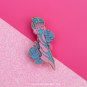 May include: Gold-tone enamel pin featuring a pink and blue hand with claws and dripping blue paint, surrounded by blue roses.