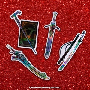 May include: A collection of holographic stickers featuring fantasy weapons and a book. The stickers include a cane, a sword, a katana, and a large sword. The background is a sparkly red surface. The text "ETSY.COM/SHOP/ANDVENCEANCEFORALL" is at the bottom.