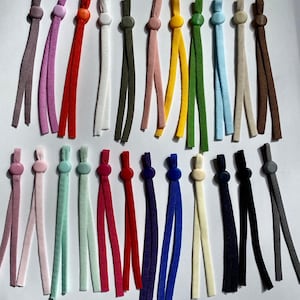 May include: Assortment of 20 colorful elastic cords with plastic stoppers. The cords are in various colors, including purple, pink, red, white, green, yellow, blue, brown, and gray. The stoppers are in matching colors.
