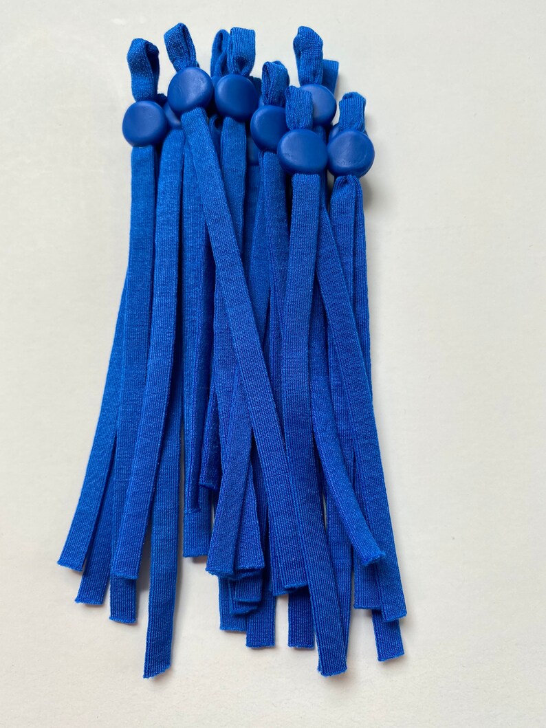 May include: A bundle of 15 royal blue elastic straps with adjustable toggles. The toggles are made of a smooth, hard plastic and are a slightly darker shade of blue than the straps.