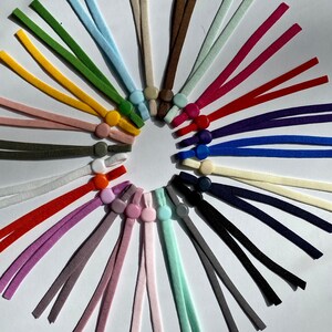 May include: A variety of colorful elastic cords with plastic slider toggles. The cords are arranged in a circle with the toggles facing outward.