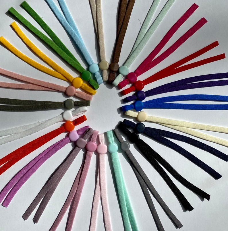 May include: A variety of colorful elastic cords with plastic slider toggles. The cords are arranged in a circle with the toggles facing outward.