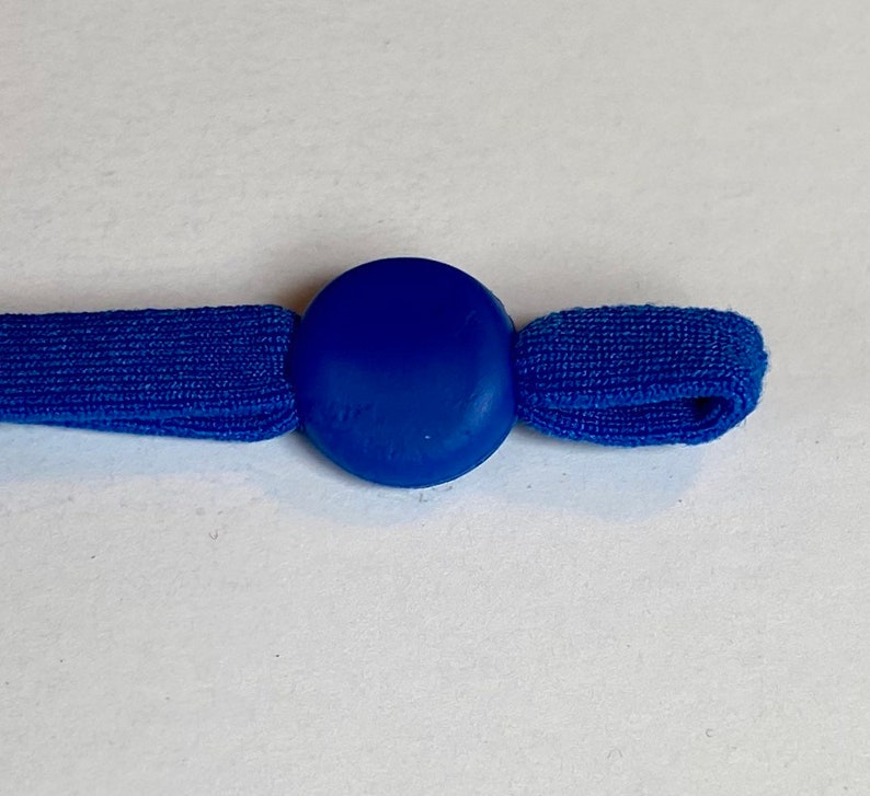 May include: A blue elastic cord with a round blue plastic toggle. The toggle is smooth and has a slight shine.